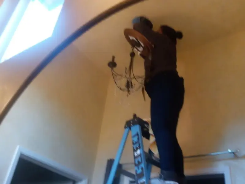 Electrician installing a chandelier in a Pomfret residence